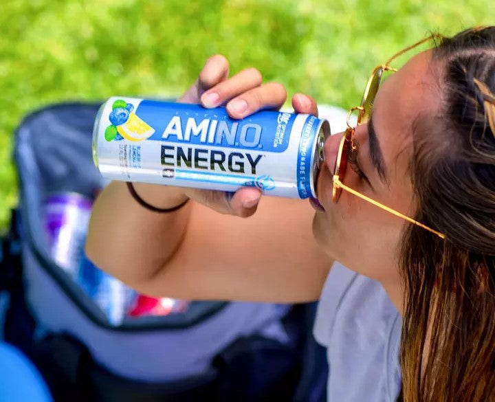 A person drinking from a can of Amino Energy, a supplement for energy and recovery