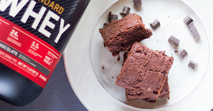 Gold Standard Whey protein powder container next to a plate with chocolate brownies and chocolate chunks