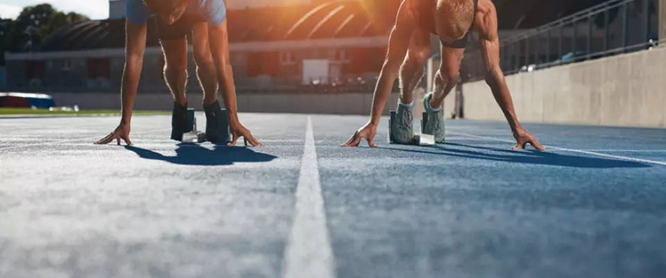 Two athletes in starting positions on a track, preparing for a sprint race